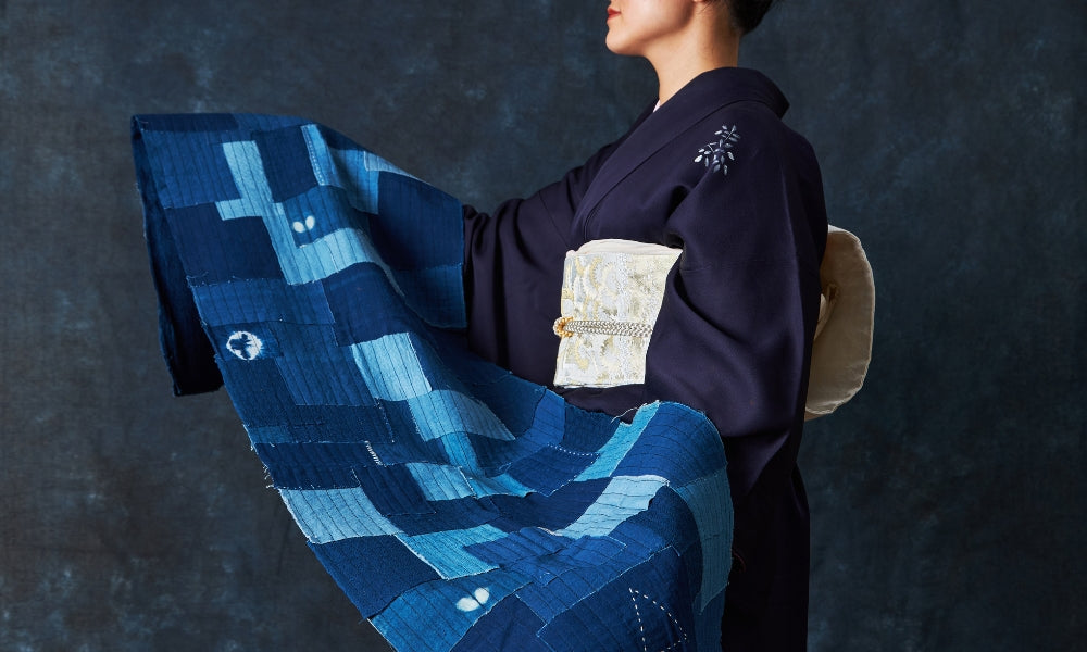 Japanisches Boro-Patchwork-Textil aus Indigo-Baumwolle mit sichtbaren Sashiko-Vorstichen, getragen von einem Model im dunklen Kimono
