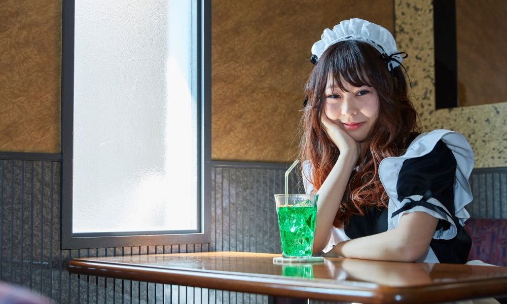 Kellnerin in Maid-Kleidung an einem Tisch in einem japanischen Maid Café in Akihabara