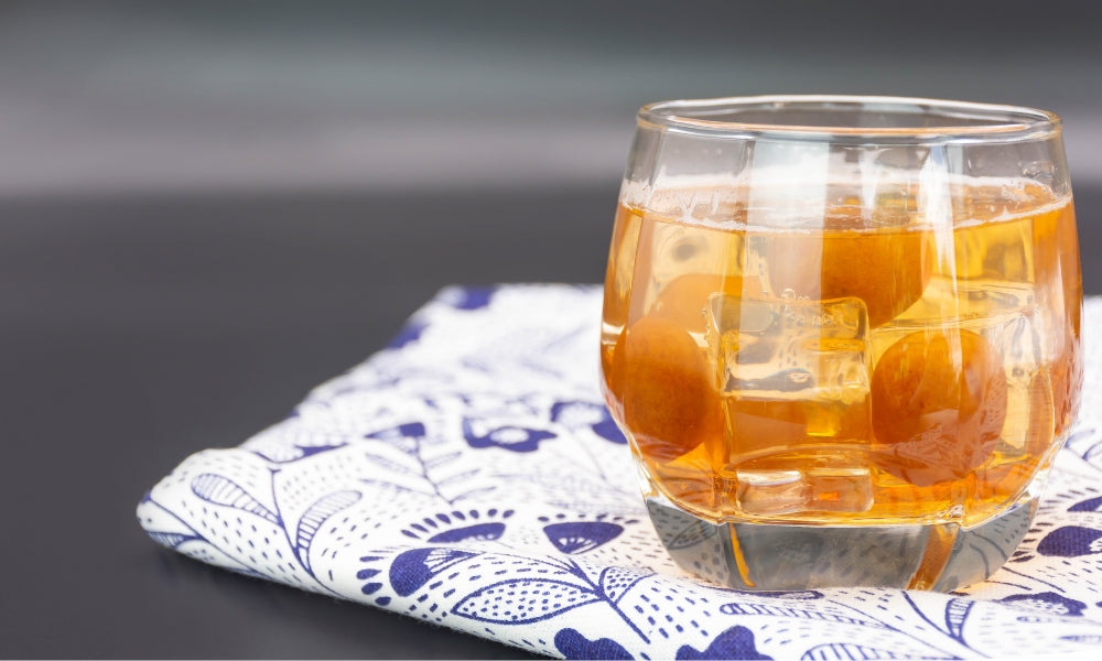 Glas Umeshu, der japanische Pflaumenwein, auf Eis serviert mit ganzen Ume-Früchten am Boden