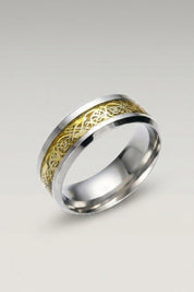 Ring 'Ringshine' in Gold — flacher Stahlring mit Mittelband, in das ein fadenfeiner Drache eingelegt ist, Produktfoto vor hellgrauem Hintergrund