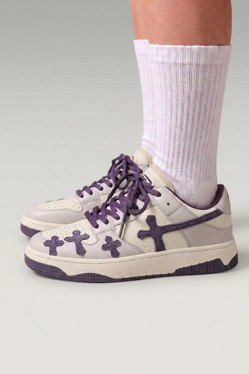 Low-Top-Sneaker 'Shiro' in Violett — geprägte Kreuze an den Seiten, dicke passende Schnürsenkel, am Fuß mit weißen Socken vor grauem Studiohintergrund