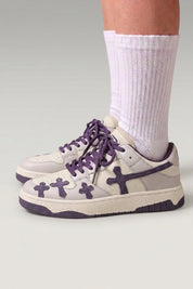Low-Top-Sneaker 'Shiro' in Violett — geprägte Kreuze an den Seiten, dicke passende Schnürsenkel, am Fuß mit weißen Socken vor grauem Studiohintergrund