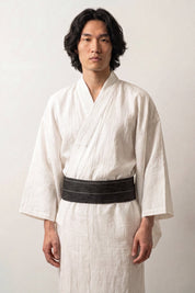 Obi-Gürtel 'Hikoma' über einem weißen Kimono von einem männlichen Model an der Taille getragen — dunkles, fast schwarzes Grün mit feinen senkrechten Webstreifen