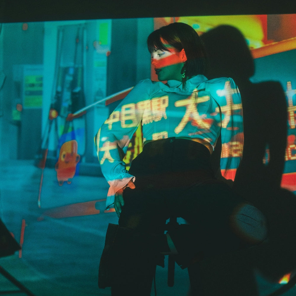Frau in streetwear-inspirierter japanischer Mode unter Neonprojektionen in Tokio – Streetwear-Universum von Japanische Kleidung