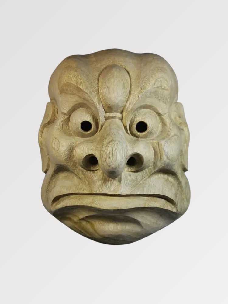 Karasu-Tengu-Maske von vorn vor einfarbig grauem Hintergrund — geschnitzter Krähen-Tengu mit markantem Schnabel, großen runden Augen und gerippter Stirn