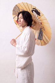 Japanischer Wagasa 'Take-Amino' geöffnet, von einem Model gehalten — ockergelbe Bespannung mit Frauenbildnis im Kimono nach Art des Holzschnitts