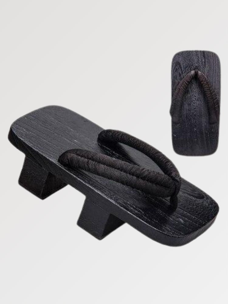 Paar Geta 'Tsushima' schräg von vorn — Sockel aus schwarz gebeiztem Holz mit zwei Stegen, schmaler weicher schwarzer Riemen, Unterseite sichtbar
