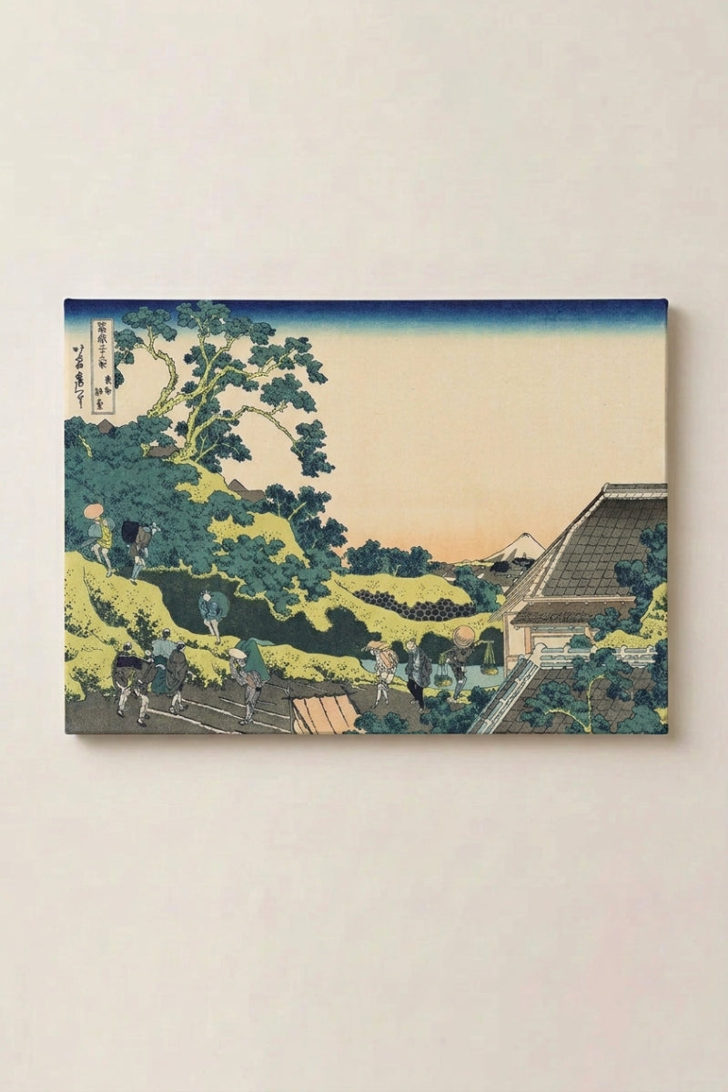 Japanischer Holzschnitt 'Shukakku' als gerahmtes Wandbild vor beiger Wand — grüner Hang mit Bäumen und das Dach eines Pavillons, hinter dem Kamm der Fuji