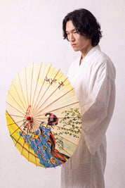 Japanischer Wagasa 'Shojino' geöffnet, von einem Model im weißen Kimono gehalten — gelb-blaue Bespannung mit Maiko-Figur und blühenden Zweigen