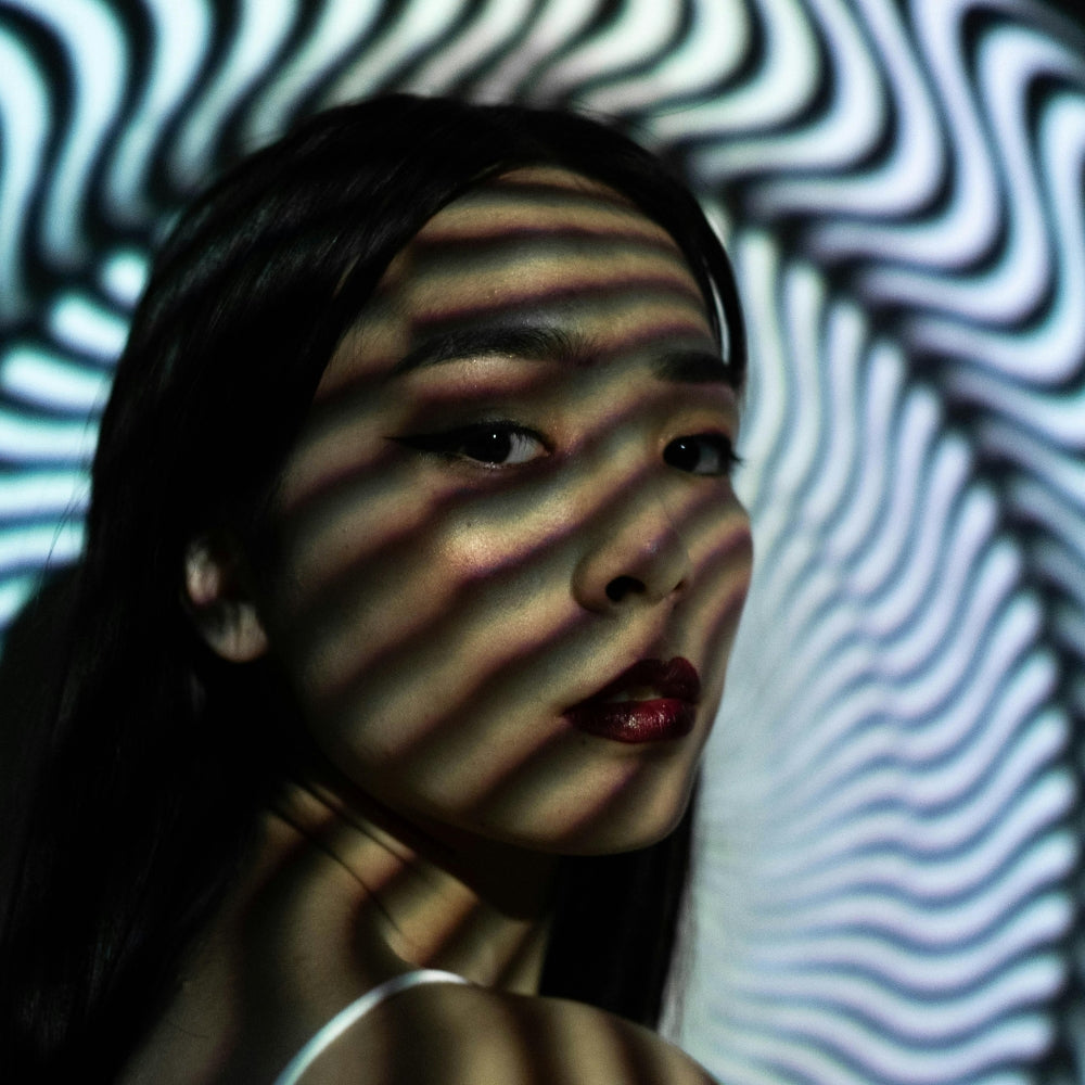 Künstlerisches Porträt einer japanischen Frau mit abstrakten Lichteffekten, das die urbane und minimalistische Ästhetik der japanischen Mode darstellt — Japanische Kleidung