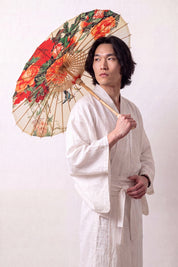 Japanischer Wagasa 'Asatsuyu' geöffnet, von einem Model im weißen Kimono gehalten — cremefarbene Bespannung mit großen orangen und roten Blüten