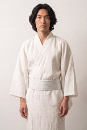 Obi-Gürtel 'Sakemi' über einem weißen Kimono von einem männlichen Model an der Taille getragen — sehr helles Grau mit unregelmäßigen weißen Strichen
