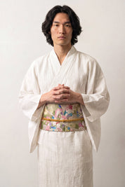 Obi-Gürtel 'Sakura' über einem weißen Kimono von einem männlichen Model an der Taille getragen — blassgrüner und goldener Brokat mit rosa Blüten und Kranichen