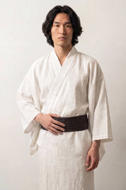 Obi-Gürtel 'Tokyo' über einem weißen Kimono von einem männlichen Model an der Taille getragen — dunkelbraun meliert mit sichtbarer, stark strukturierter Bindung