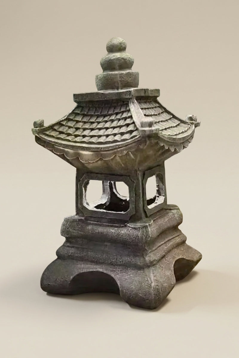 Japanische Laterne — traditionelle Bronzelaterne mit übereinanderliegenden Dächern, durchbrochenem Korpus und massivem Bogensockel, Foto vor beigem Grund