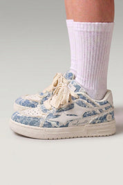 Low-Top-Sneaker 'Seiryu' in Blau — Canvas in Washed-Optik mit verlaufendem Blumenmuster, cremefarbene Cupsole, am Fuß mit weißen Socken im Studio