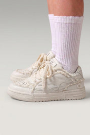 Low-Top-Sneaker 'Seiryu' in Weiß — Canvas in Washed-Optik mit verlaufendem Blumenmuster, cremefarbene Cupsole, am Fuß mit weißen Socken im Studio